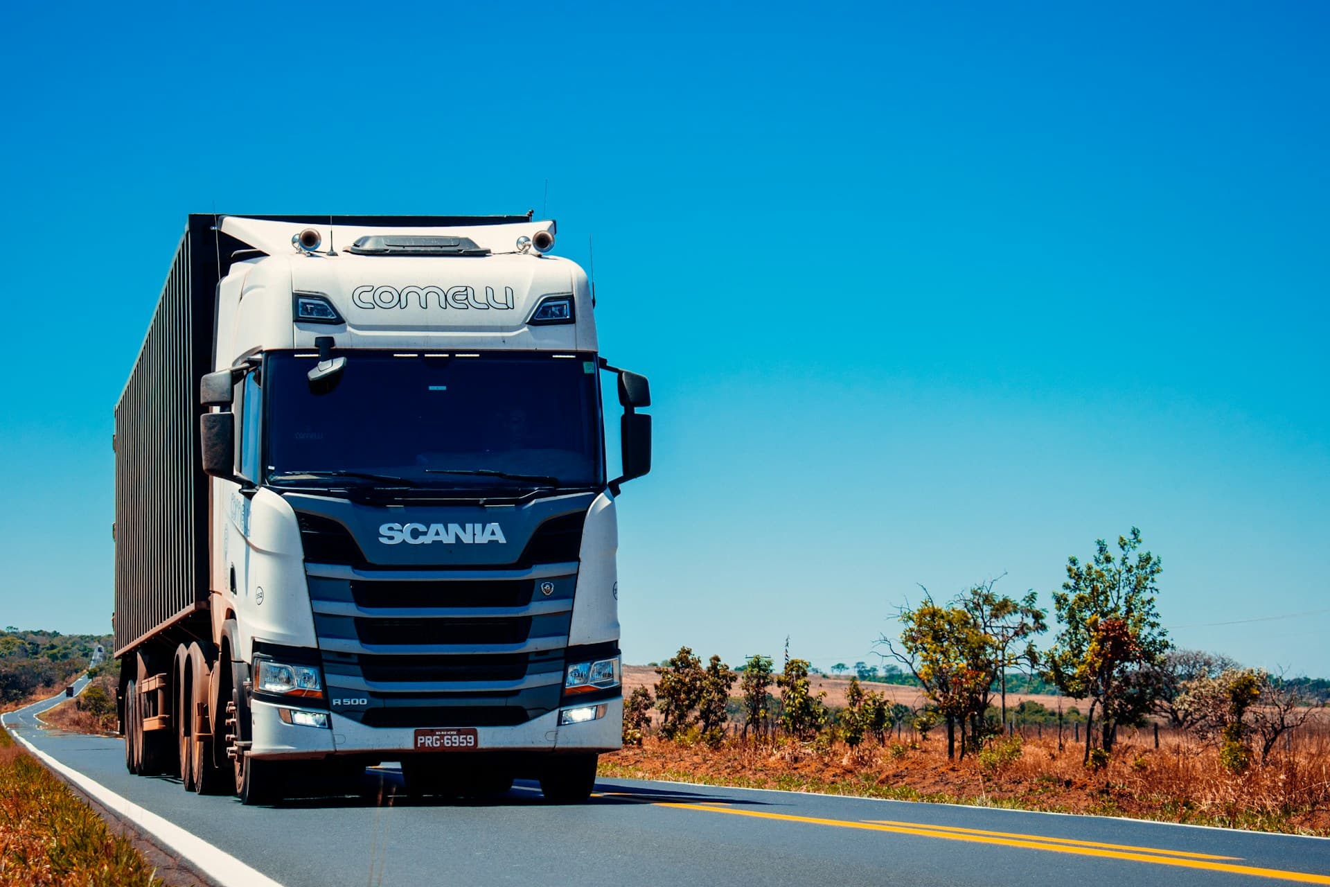 White semi-truck hauling a container along a sunny highway